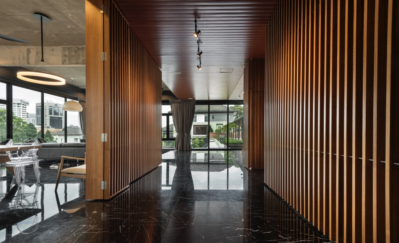 Open dining area with timber screens, exposed concrete ceiling, and glass walls connecting to outdoor terrace