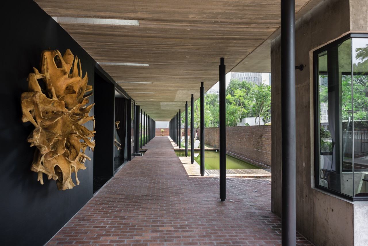 Gallery space with sculptural timber element and view through to landscape, showing material layering approach