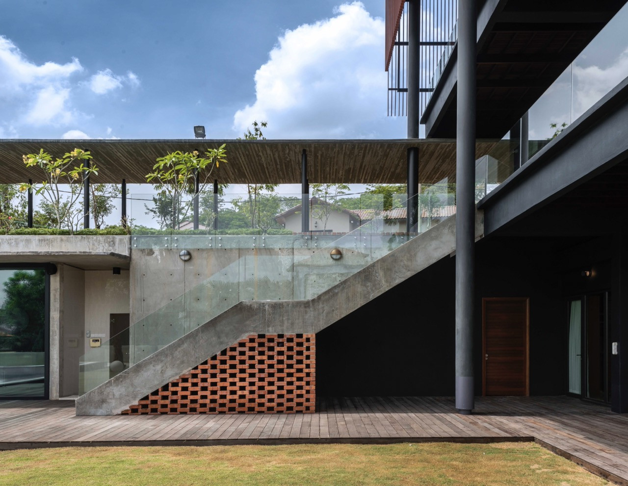 Concrete staircase with glass balustrades connecting levels, raw concrete left exposed