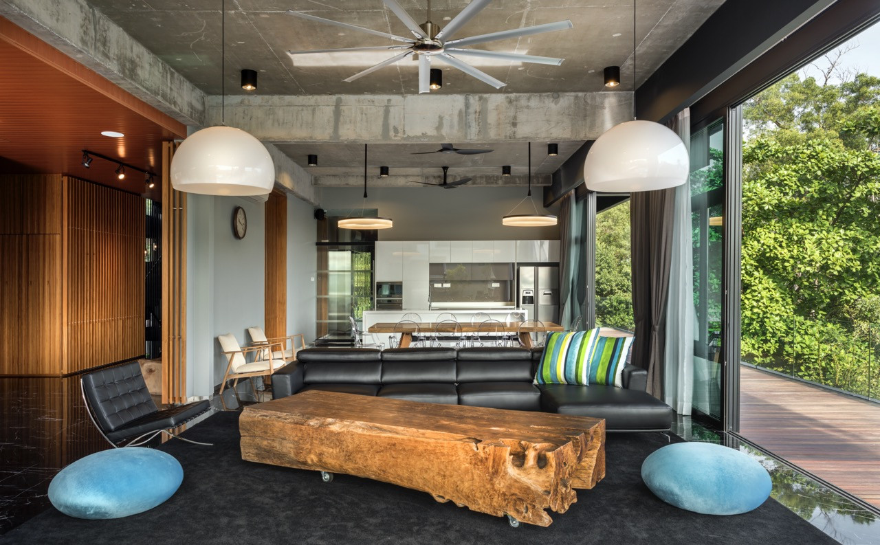 Open-plan living area with exposed concrete ceiling, natural timber surfaces, and contemporary furniture arrangement