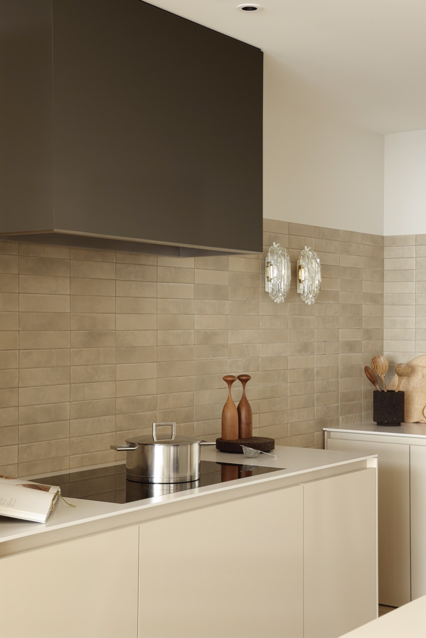 Crystal wall sconces add glamour to the Spanish porcelain tile backsplash, with the flush-mounted hob maintaining clean lines in the open-plan kitchen design