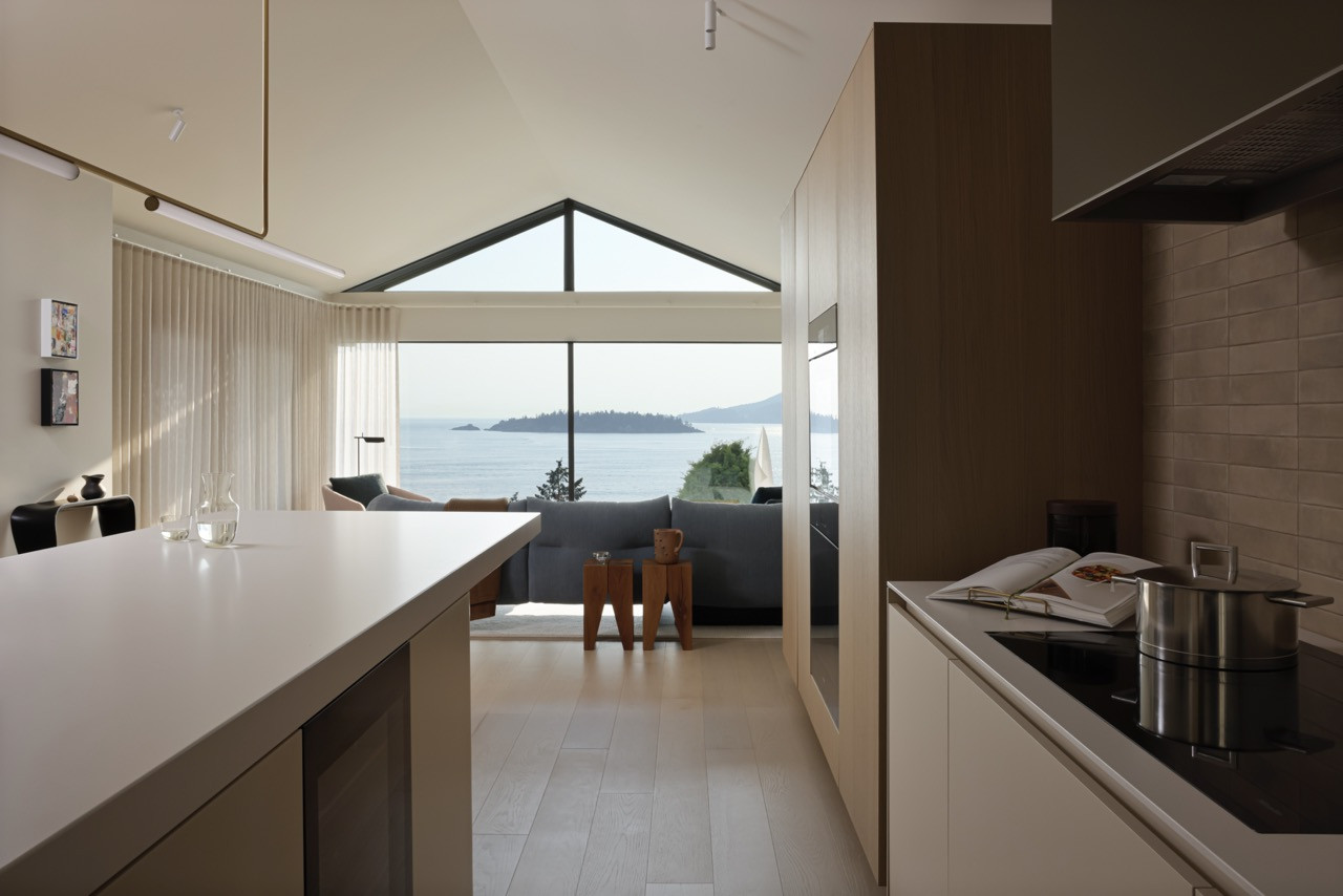 The kitchen opens to the main living areas, creating continuous sightlines toward the water beyond, whilst maintaining discreet integration of Miele appliances