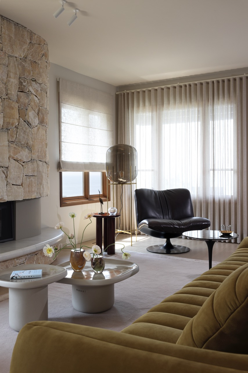 The living area showcases the curved onyx fireplace with its honey and amber-hued stone, carefully preserved and reinstalled by master stonemason Robb Webb to maintain the home's 1975 character