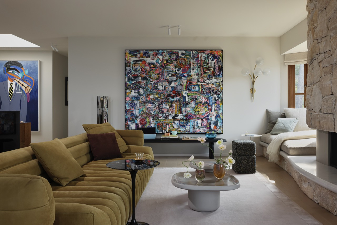 The family room showcases both paintings by David Nazari and collages by Michiel Folkers, with the curved onyx fireplace serving as a focal point rather than visual barrier to the spectacular water views