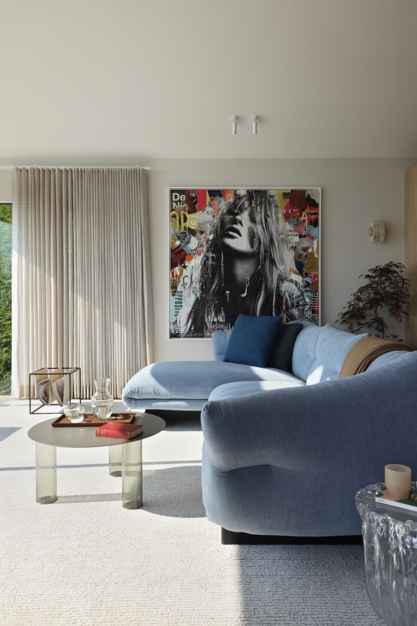 The family room showcases contemporary art and sculptural furnishings, with the open-plan design allowing natural light to flow throughout the interconnected living spaces.