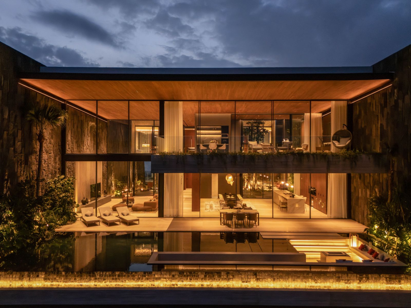 In the evening, when the interiors glow, the uppermost floor of the tropical home appears as a thin, floating slab held aloft by glass (Photo: Indra Wiras)