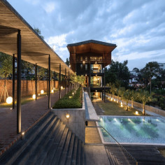 Evening view of the tropical modern house with timber louvre screens and integrated landscape lighting, creating a  warm facade