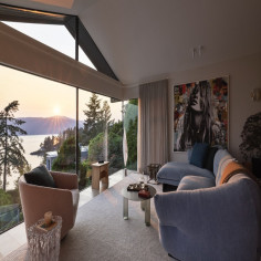 The family room features the Moncloud sectional by Cassina in this West Vancouver renovation, with floor-to-ceiling windows framing spectacular views whilst contemporary art creates a gallery-like atmosphere throughout the space
