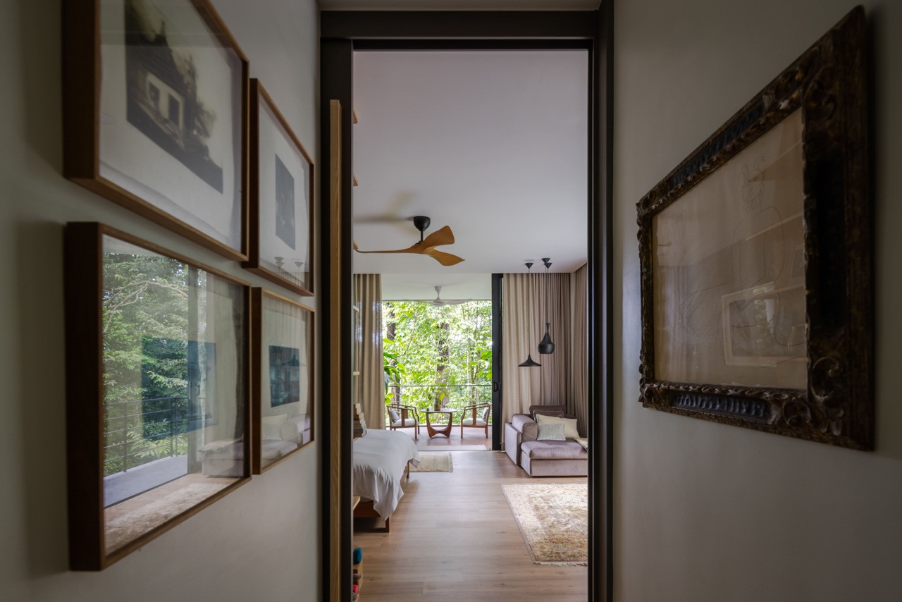 The master bedroom opens directly to forest views, furnished with carefully selected pieces that reflect the owners’ eclectic taste, from vintage mirrors to contemporary lighting