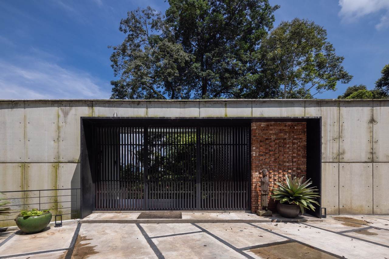 The imposing concrete entrance features minimal window openings and severe geometry, giving way to spatial surprises once inside the home