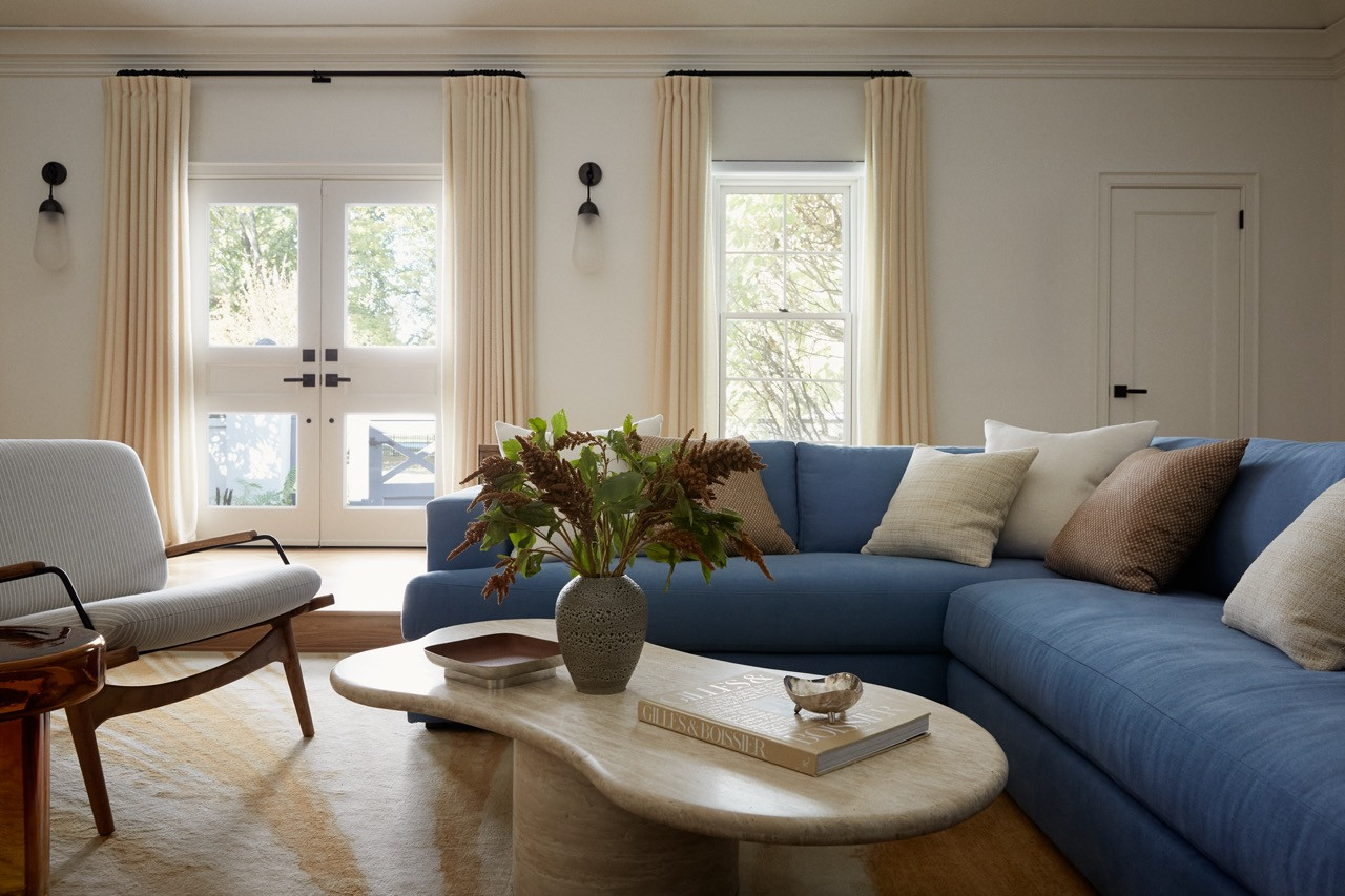 Another view of the stepped-down living room reveals the careful balance of vintage and contemporary pieces anchored by custom L-shaped bookshelves from local woodworker East Otis
