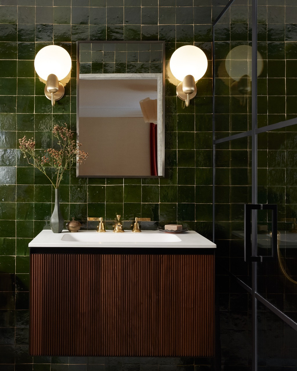 A secondary bathroom continues the bold colour approach with emerald zellige tiles floor-to-ceiling, creating an enveloping jewel-box effect