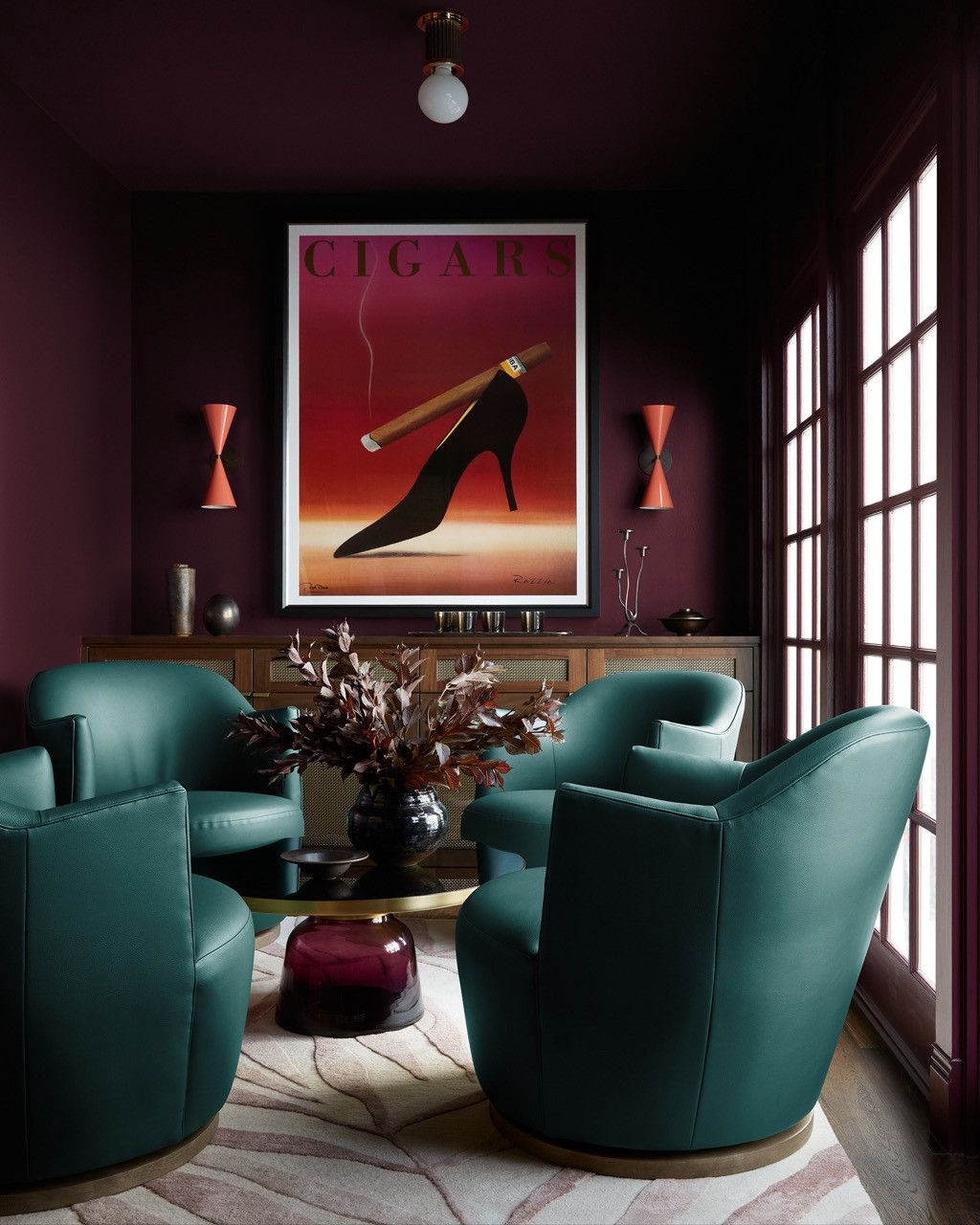 The bar room in deep plum showcases turquoise leather swivel chairs arranged around a vintage cigar poster, creating an intimate space for conversation and cigars