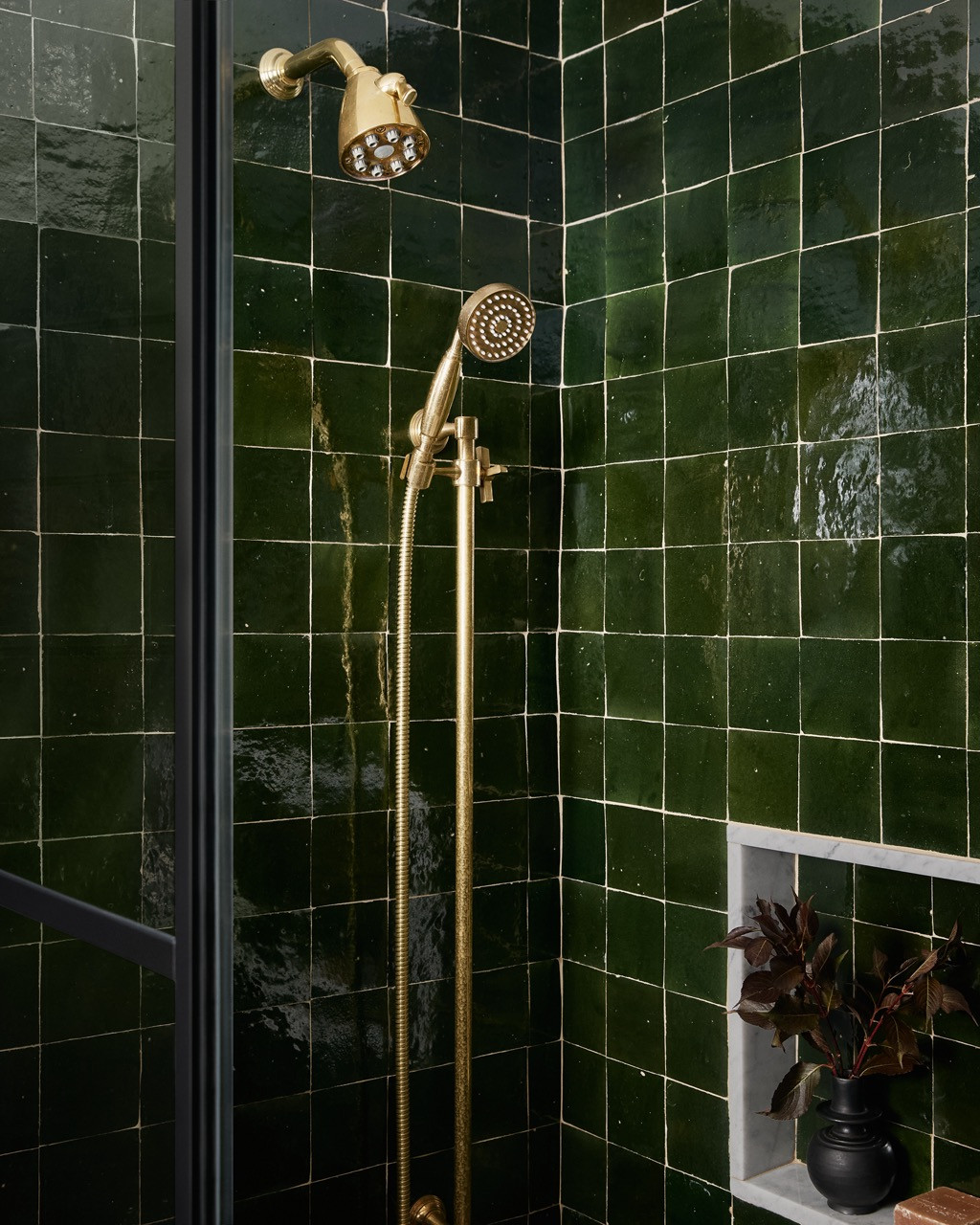 Emerald zellige tiles create an immersive bathroom experience, paired with brass fixtures that provide warm metallic contrast against the saturated green walls