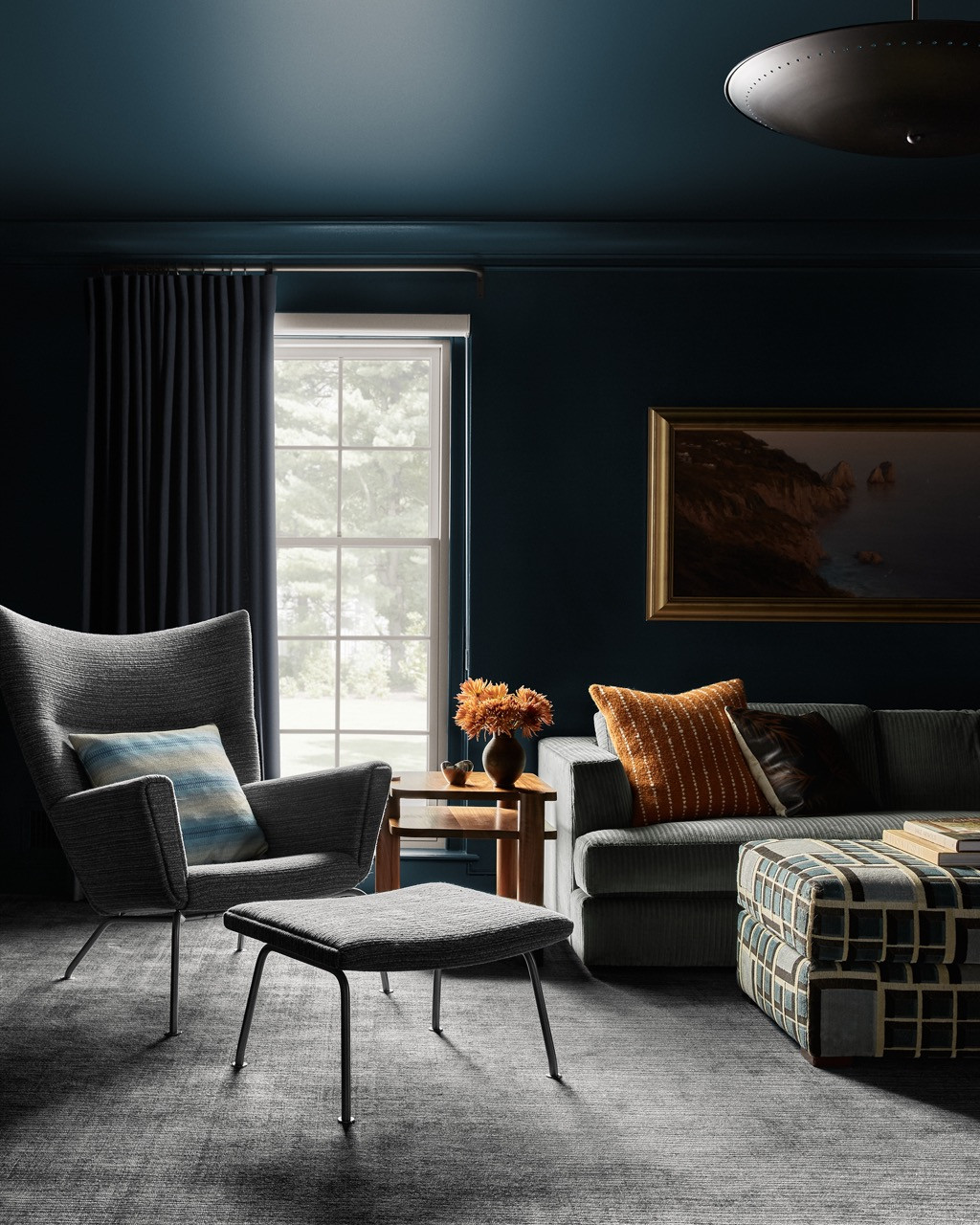 The den embraces Farrow & Ball’s midnight “Hague Blue” on walls and ceiling, creating an enveloping atmosphere. Wall-to-wall carpet by Rosecore adds softness, whilst vintage Czech chairs reupholstered in Rogers & Goffigon fabric provide comfortable reading spots
