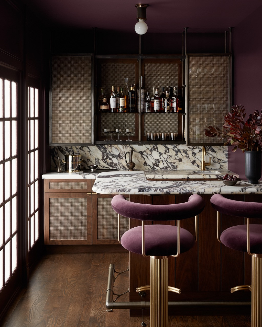 A full view of the bar, designed collaboratively with architect Neil Young, features laterally moving mesh metal shelves behind glass doors
