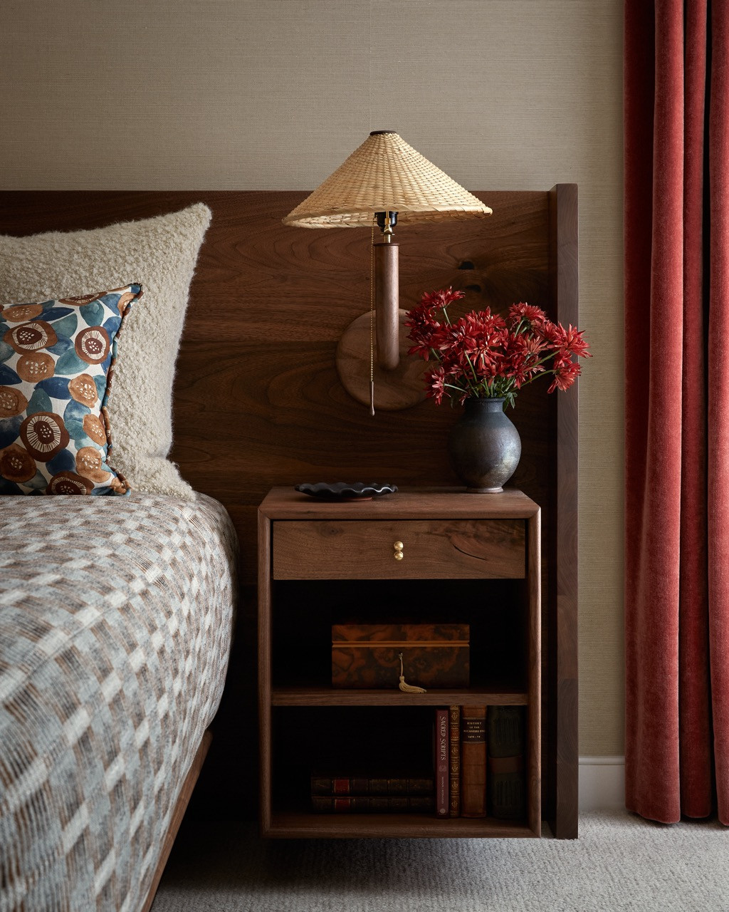 One of the two bedrooms showcases warm tones with burnt orange accents and wheat hues. The walnut nightstand by Lawson Fenning features open shelving for book storage