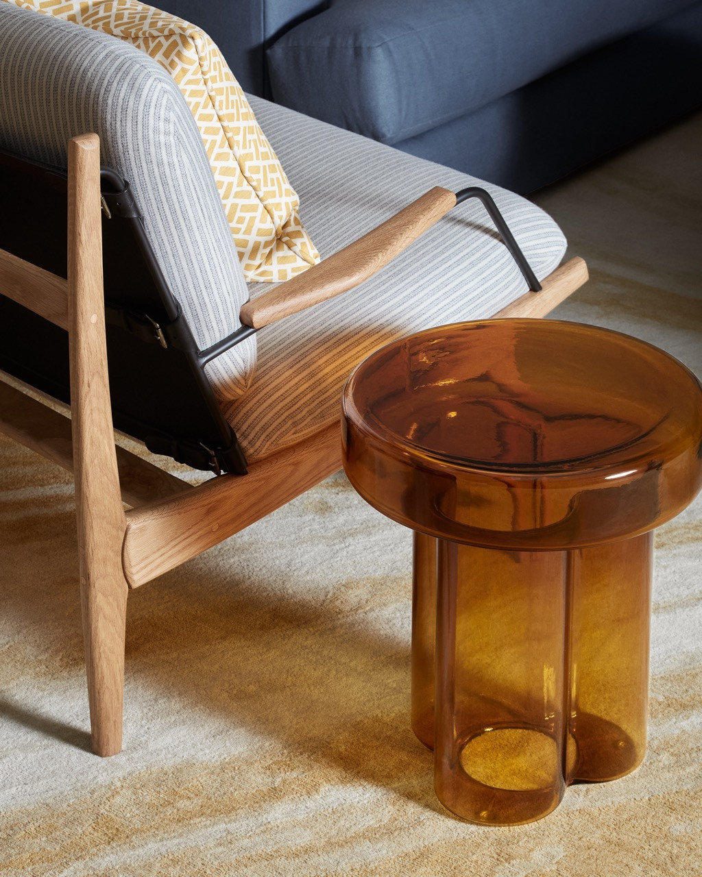 Detail of living room furnishings showing an amber glass side table paired with a vintage Czech chair.