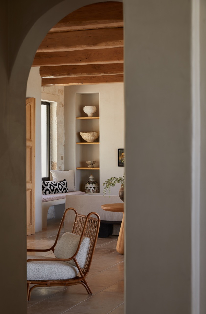 An arched doorway frames a view through to the living space with exposed wooden ceiling beams and built-in shelving