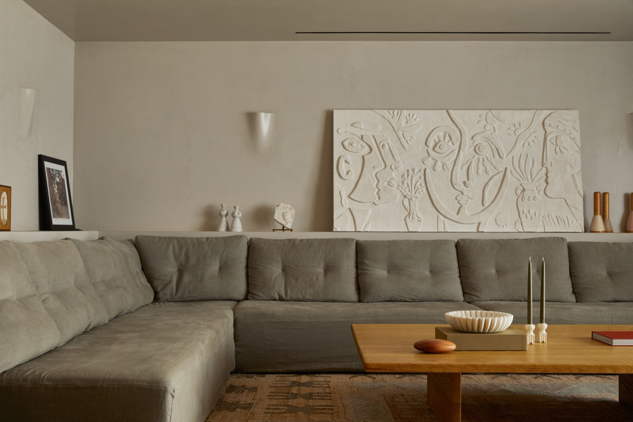 A large white relief artwork with abstract figurative motifs hangs above the custom sectional sofa in the movie room