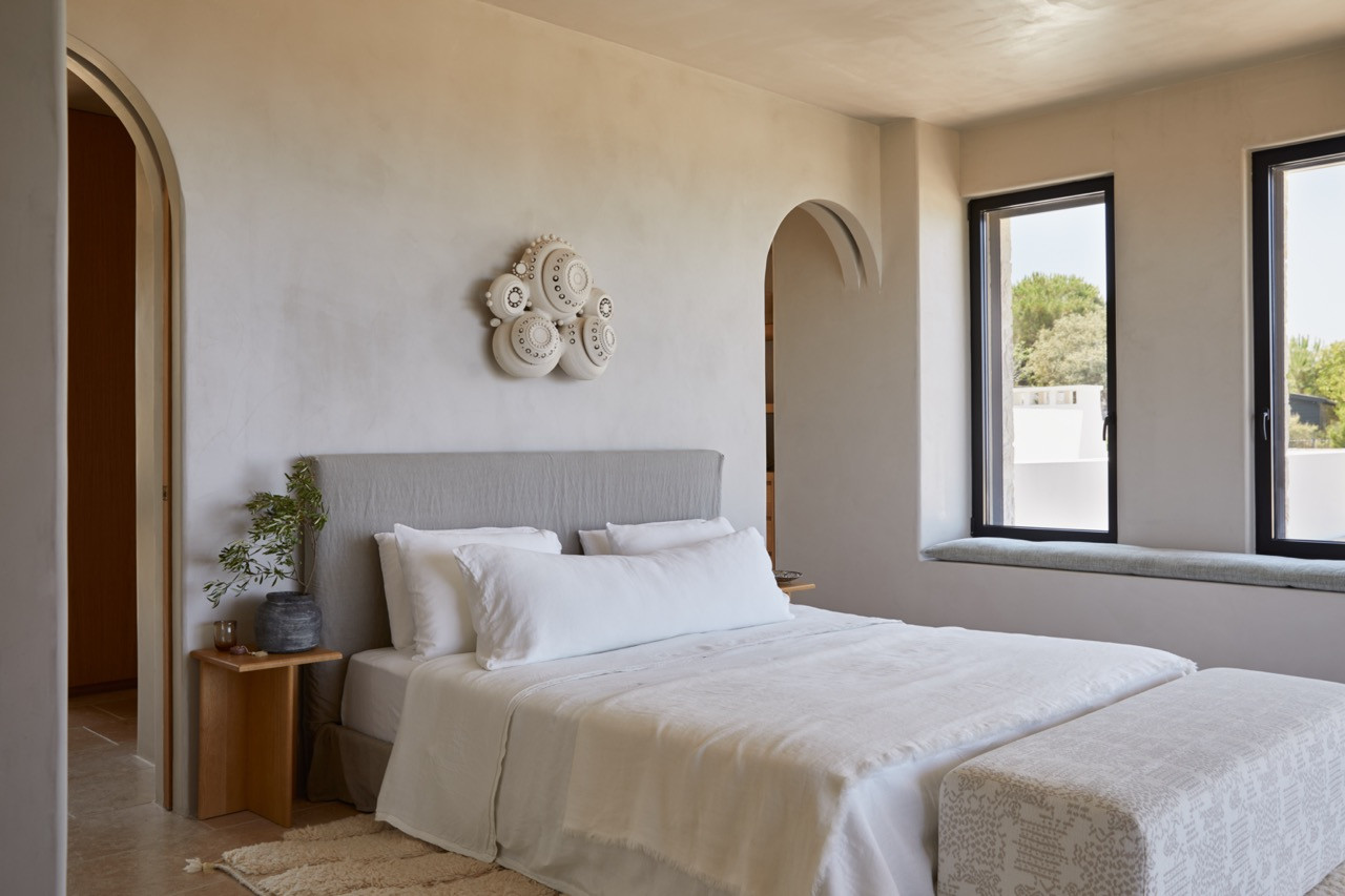 A bedroom features decorative ceramic plates mounted above the custom bed, with an arched passage and window seat visible beyond