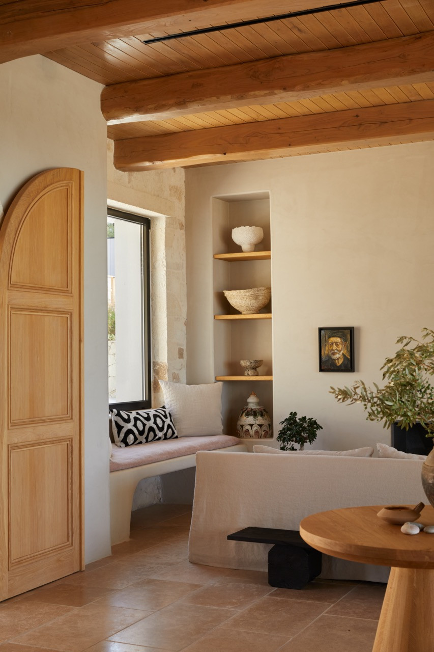 Hand-cut wooden ceiling beams crown the main bedroom's built-in window seat niche with open shelving displaying traditional ceramics and decorative objects