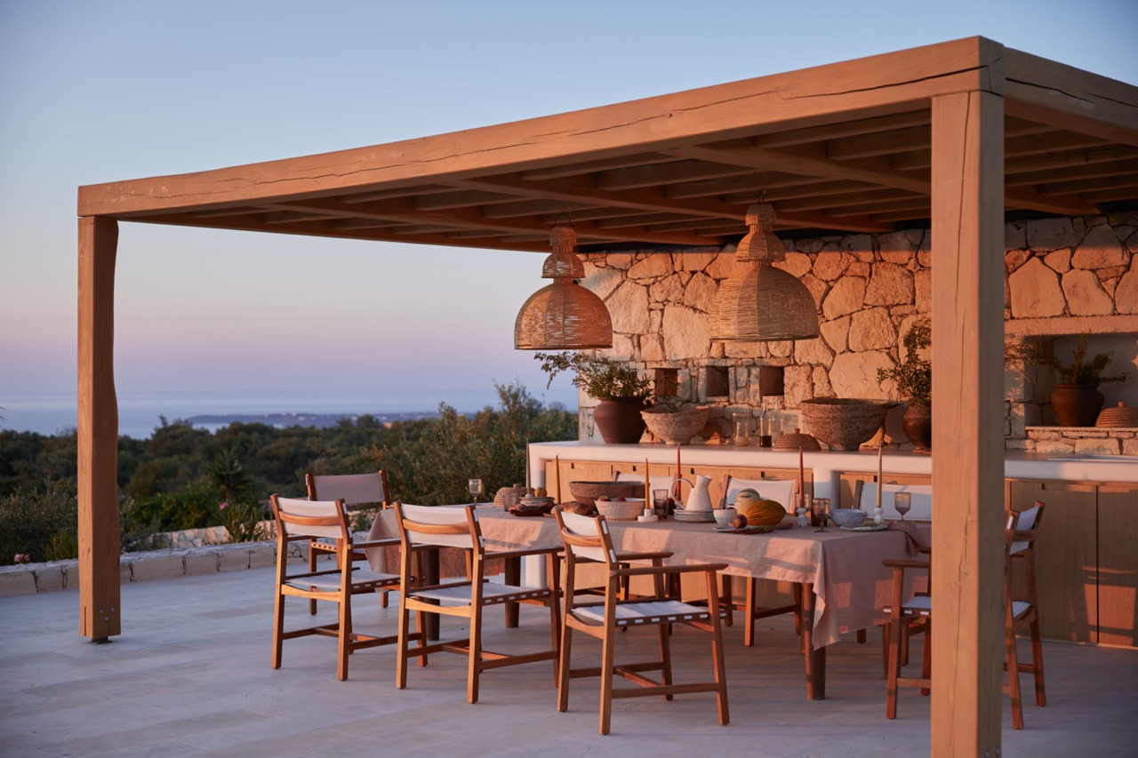 Palm trees flank the outdoor dining pavilion beside the pool with mountain views across the Cretan landscape