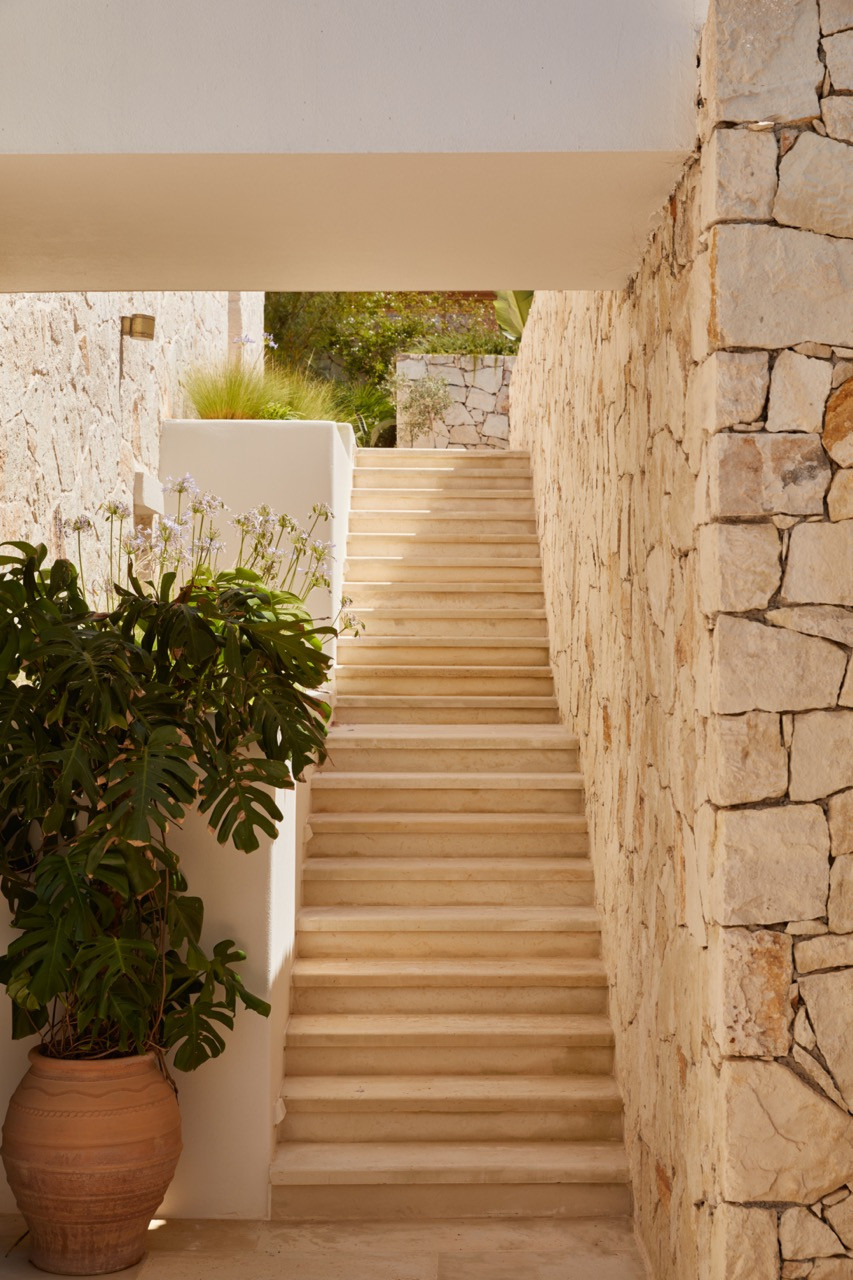 Stone stairs connect the property's levels between hand-chiselled walls with a terracotta planter holding foliage at the base