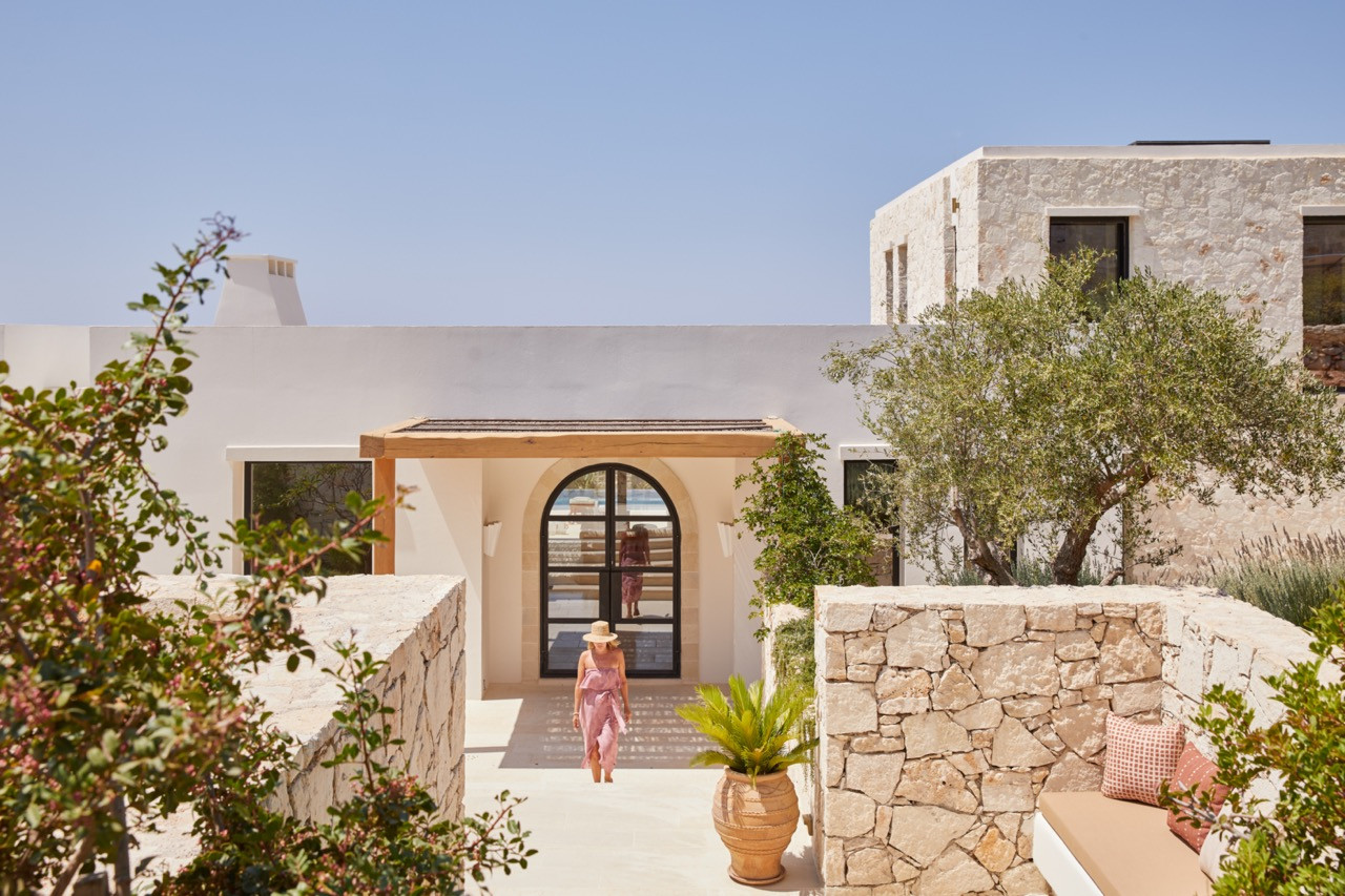 The property's exterior shows stone walls and white plastered surfaces with an arched doorway leading to interior spaces