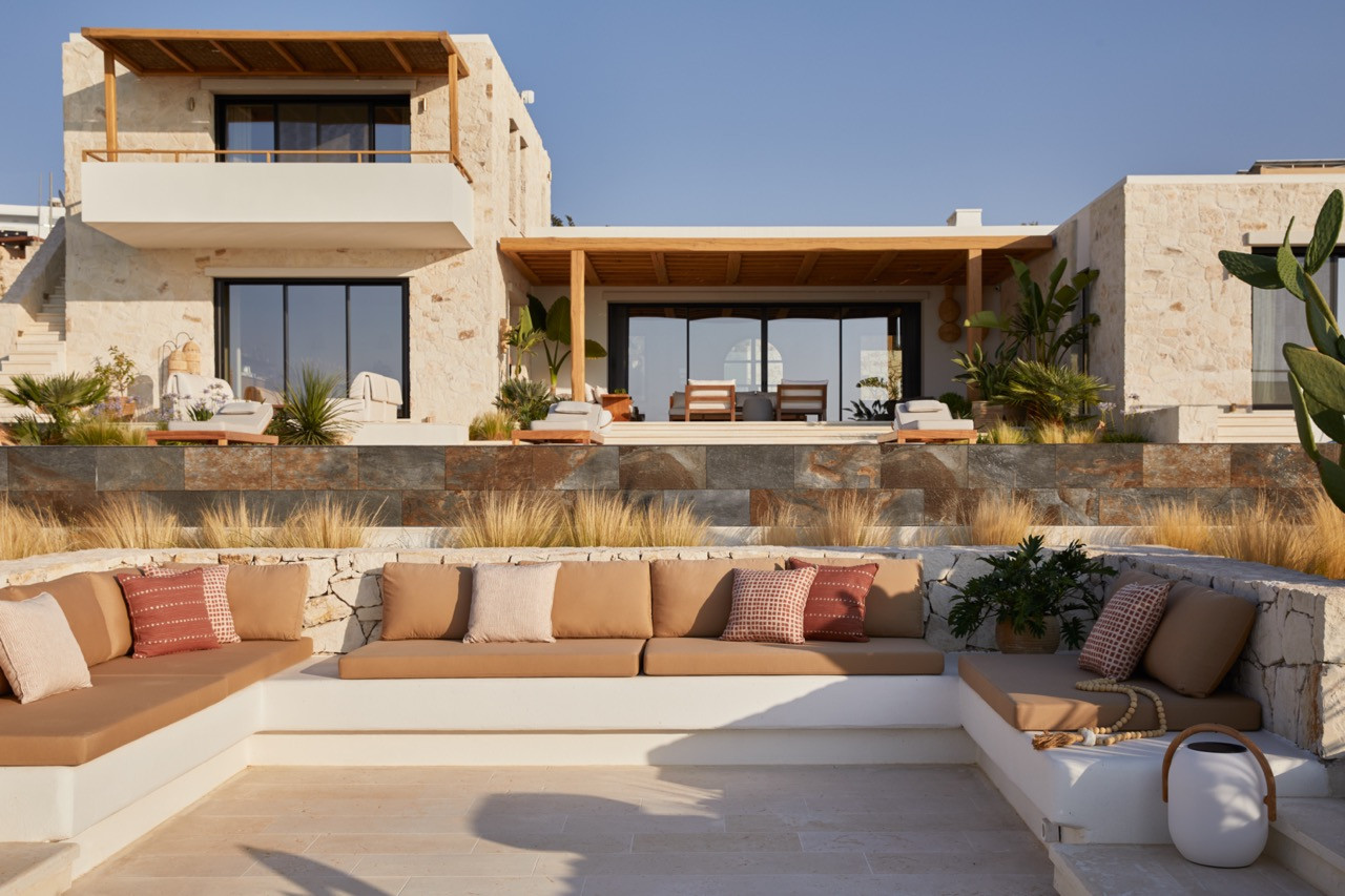 The stone residence features a distinctive Π-shaped layout with hand-cut wooden pergolas and terraced outdoor seating areas