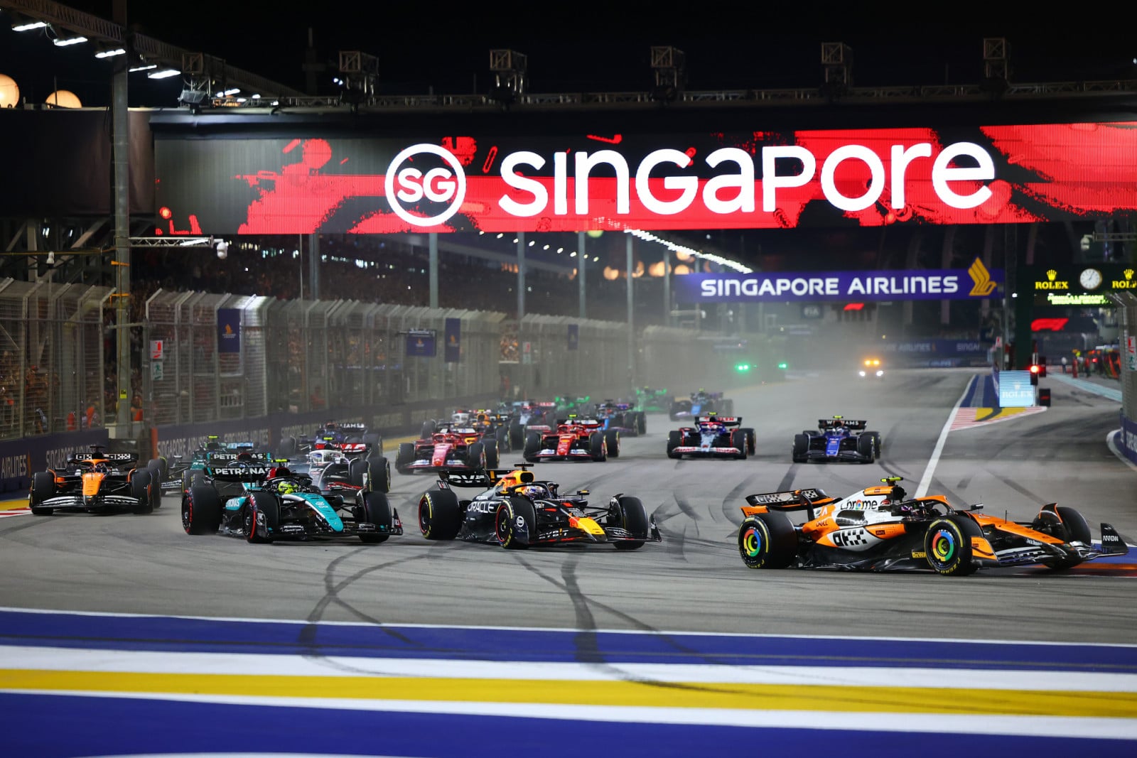 Lando Norris of the United Kingdom and McLaren Formula 1 Team, Max Verstappen of the Netherlands and Red Bull Racing-Honda RBPT, and Lewis Hamilton of the United Kingdom and Mercedes-AMG Petronas F1 Team drive on the opening lap of the F1 Grand Prix of Singapore at Marina Bay Street Circuit in Singapore, Singapore, on September 22, 2024. (Photo by Morgan Hancock/NurPhoto via Getty Images)