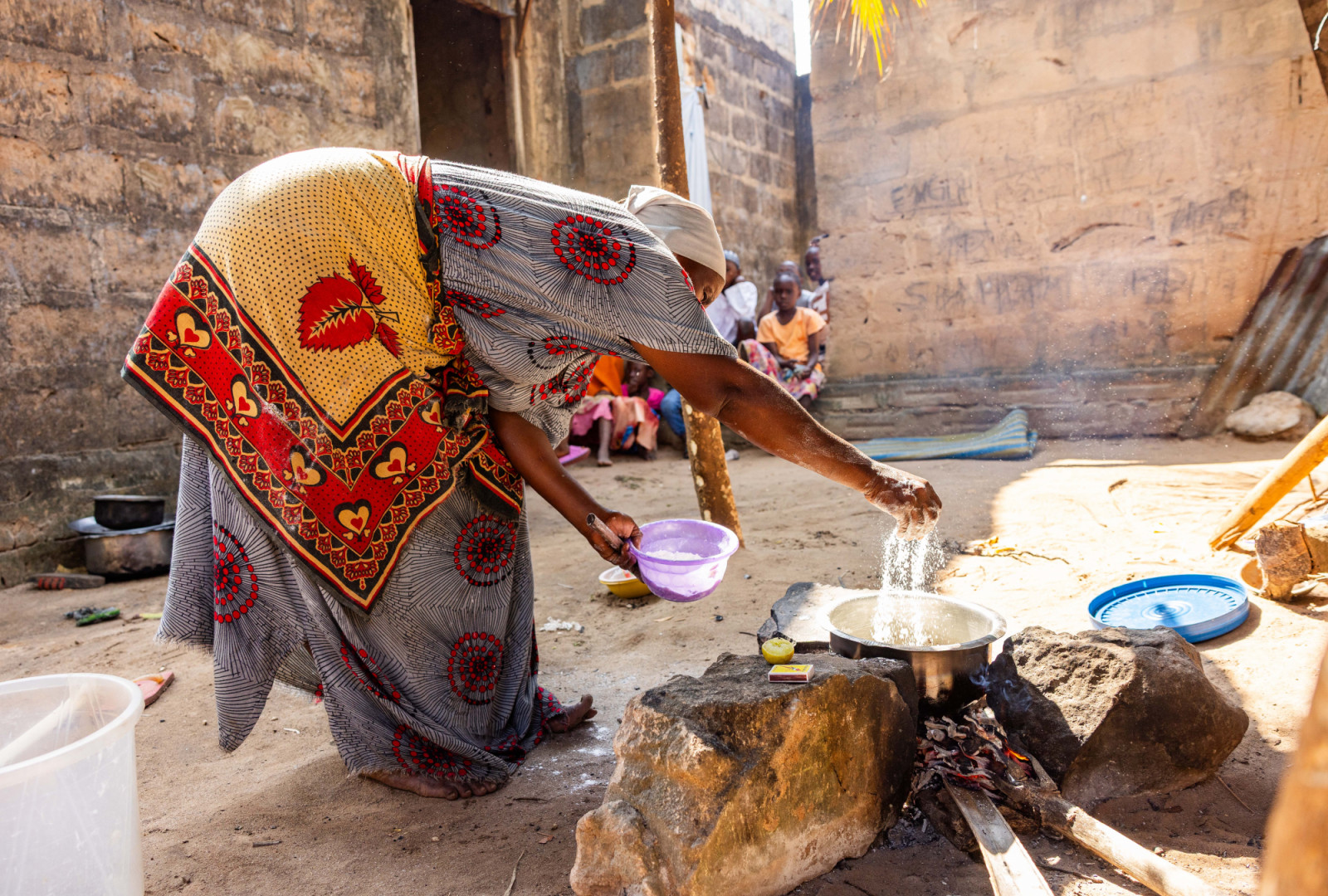 In Vikindu village, Tanzania, a woman is pictured mixing the ingredients for ugali, a traditional dish made with fortified flour, while children and community members look on. They are among the millions of people who now have access to flour fortified with essential nutrients.
