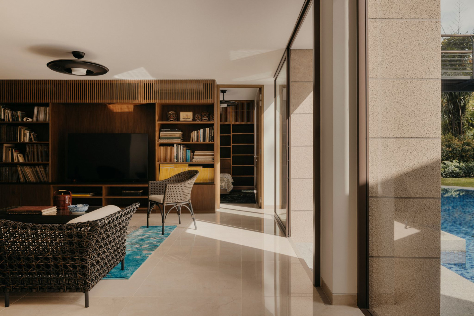 Woven chairs and timber carpentry bring a nostalgic feel to the TV room, while a blue rug introduces a pop of colour