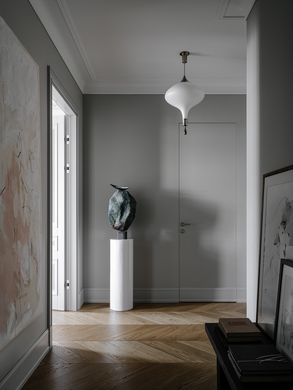Grey hallway with sculptural art piece on white pedestal, vintage pendant light and view through to master bedroom with Murano chandelier