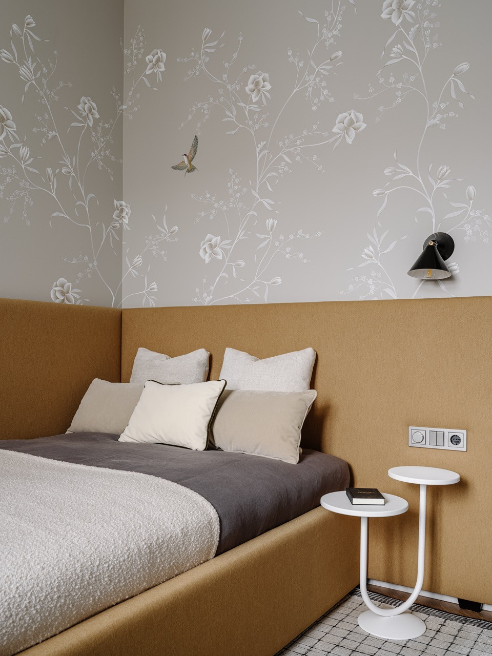 The children’s bedroom features Fresq wallpaper with delicate floral and bird motifs, with a bed by Dantone Home and a wall light by Atelier Areti