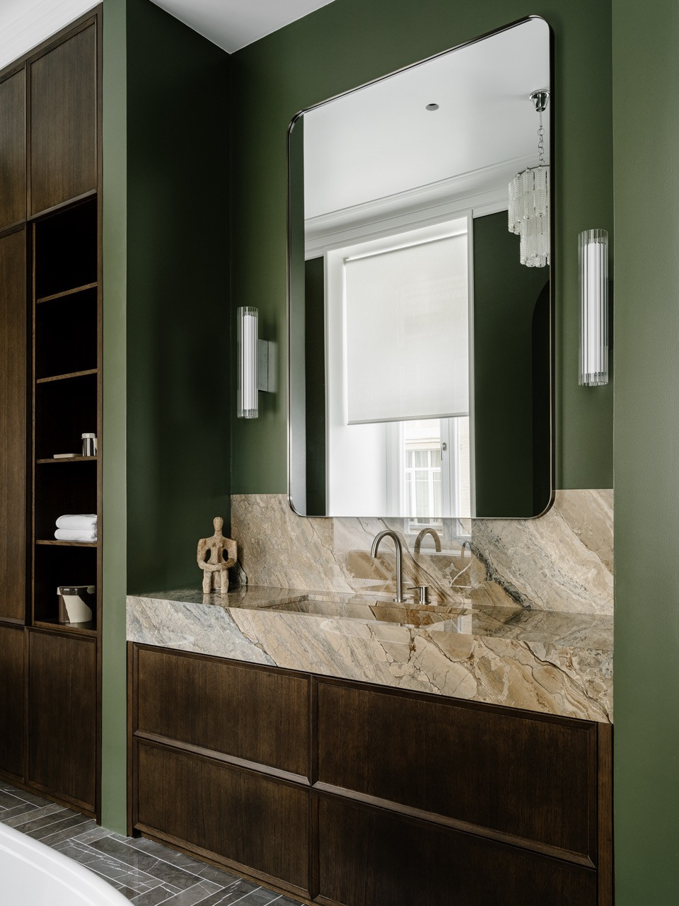 The master bathroom is painted in bold olive green tones, featuring a custom-designed vanity unit with a marble worktop and a large mirror