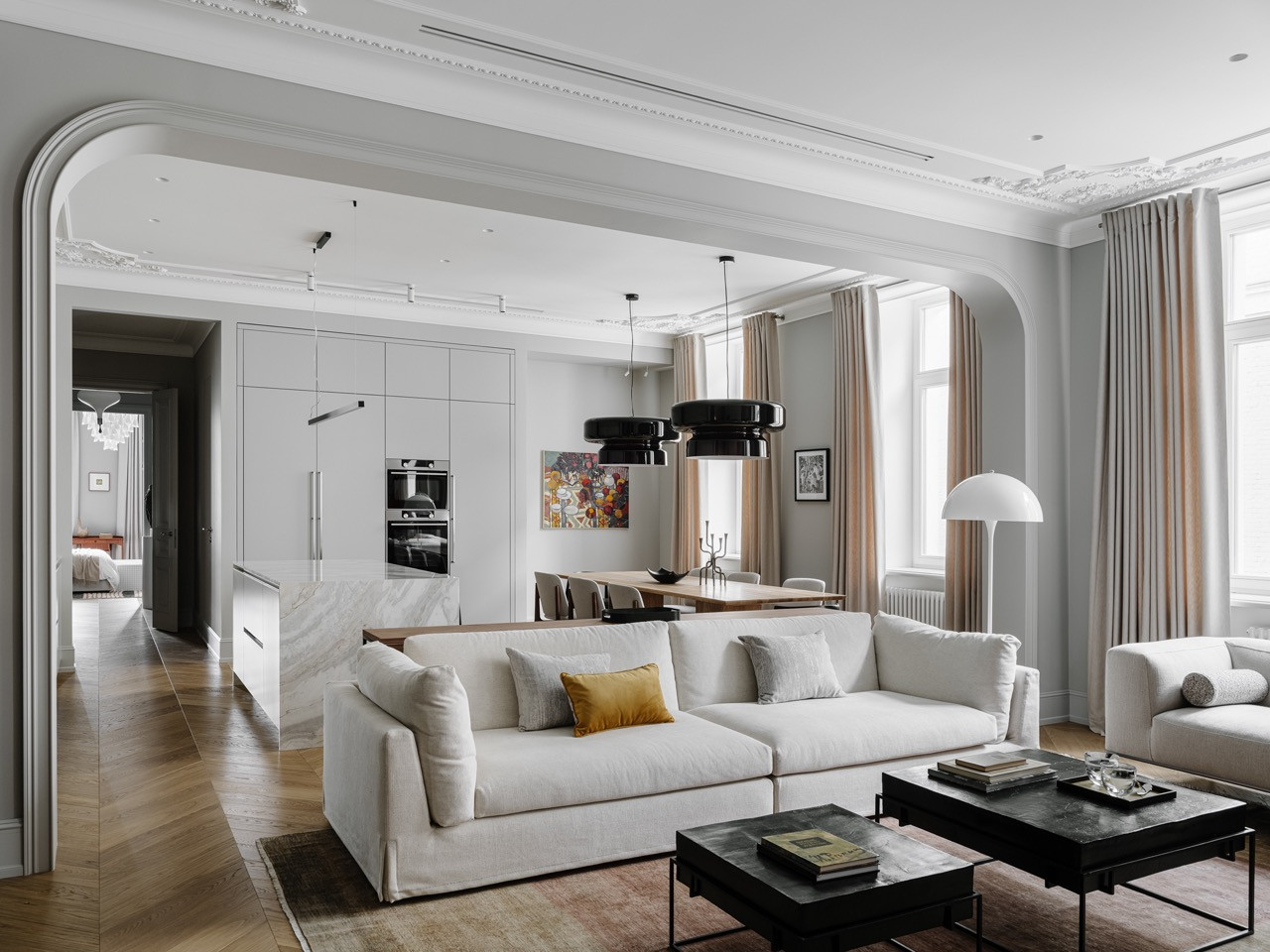 Living and dining area viewed through an arched doorway showcasing herringbone parquet, ornate mouldings and an enfilade layout to master bedroom