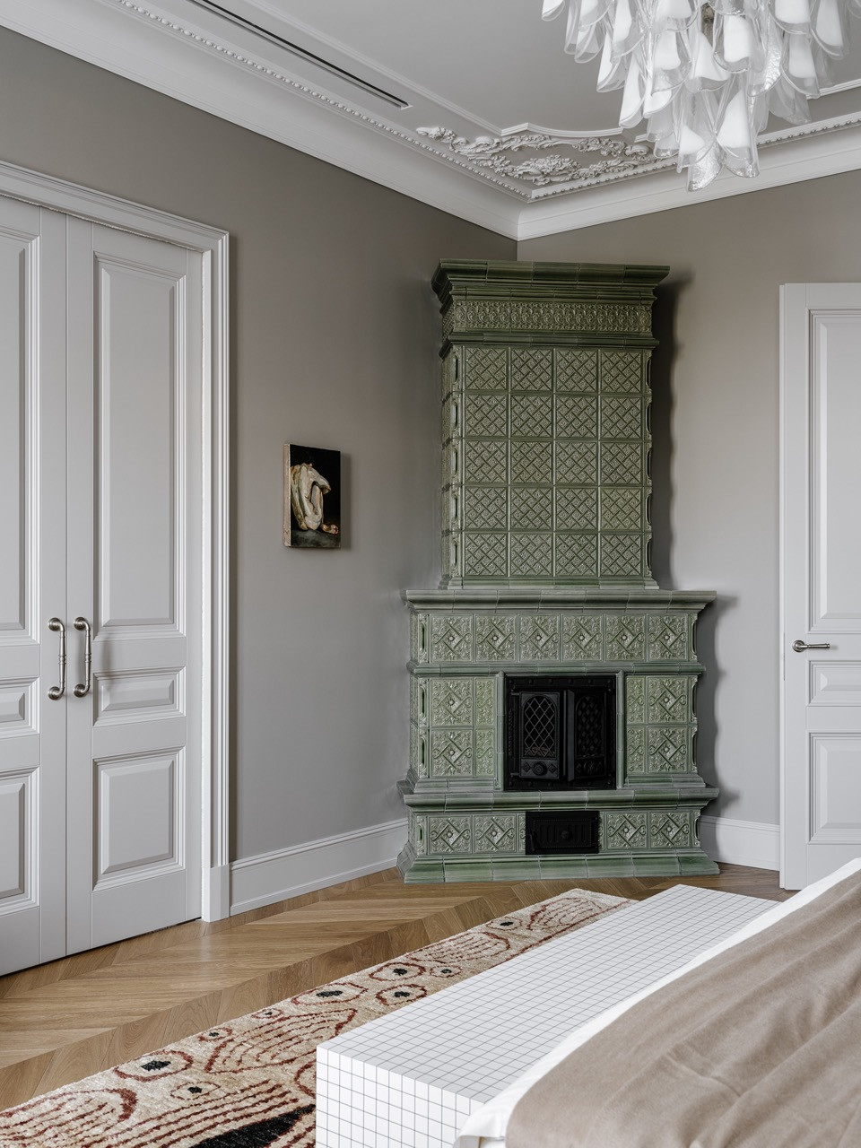The custom-designed tiled stove stands between double doors in the master bedroom with a Meridiani bed and vintage Murano chandelier overhead