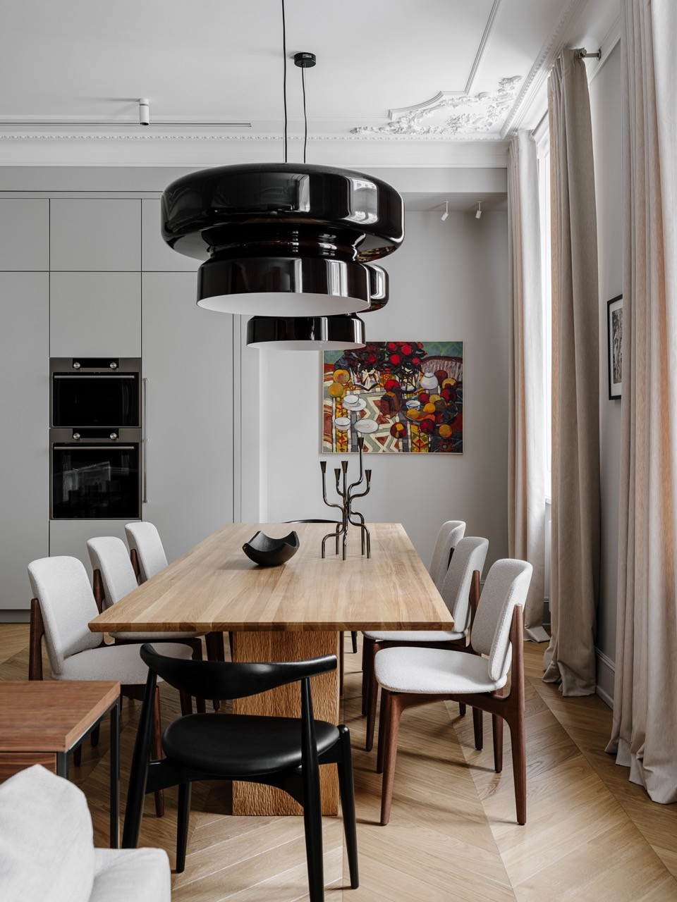 Dining area showing custom table with mix of seating and vibrant artwork visible from kitchen with marble surfaces