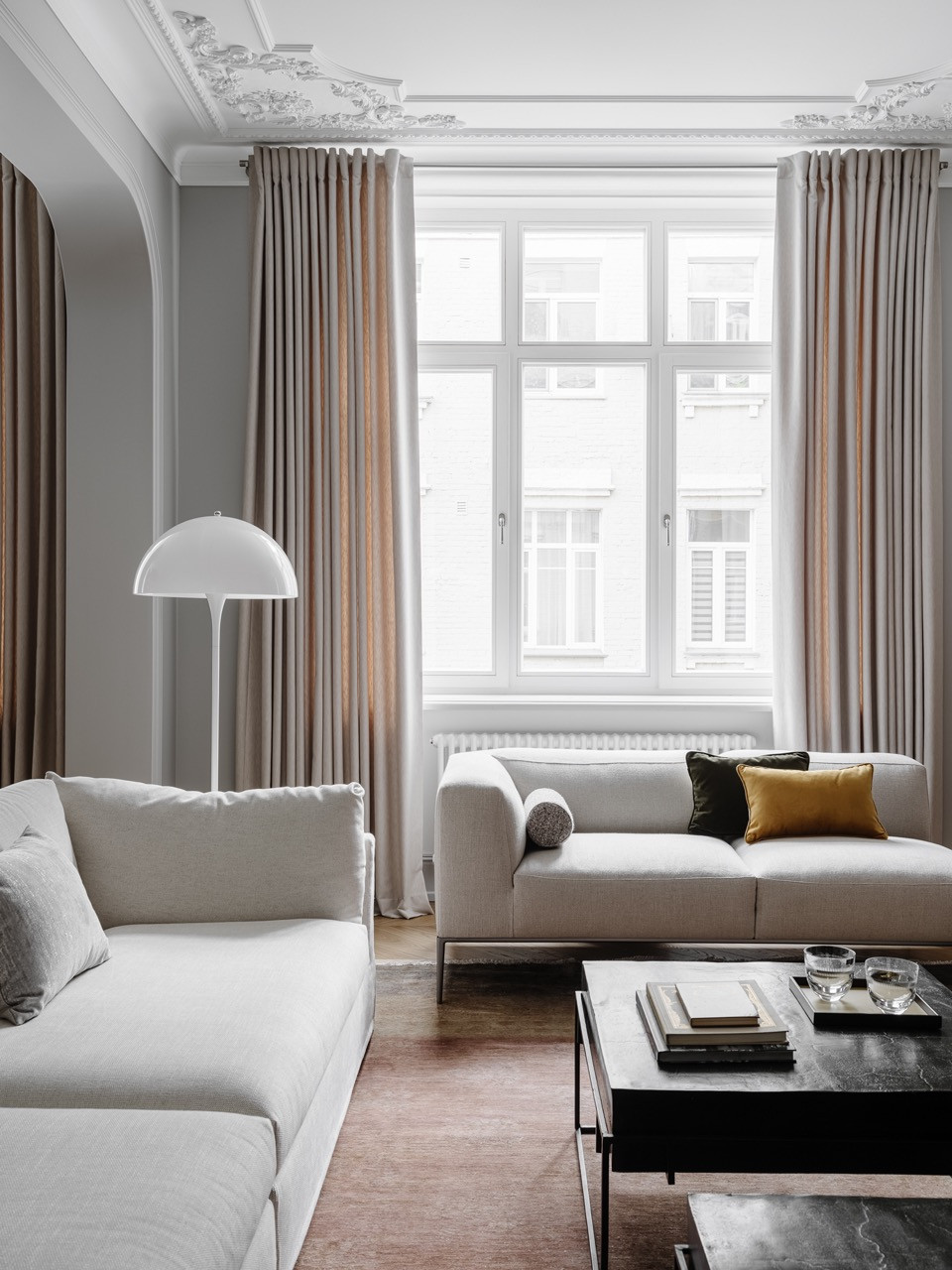 Living room with Frigerio sofa, B&B Italia sofa-bench by window and floor lamp by Louis Poulsen beneath ornate ceiling mouldings