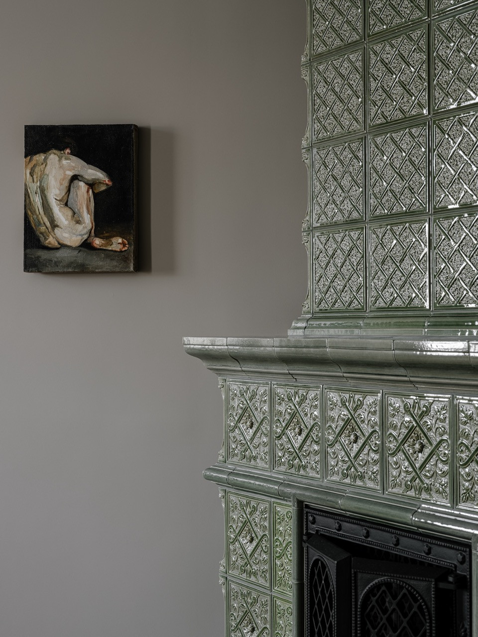 The custom-designed tiled stove in soft green tones, a rare traditional element in the master bedroom