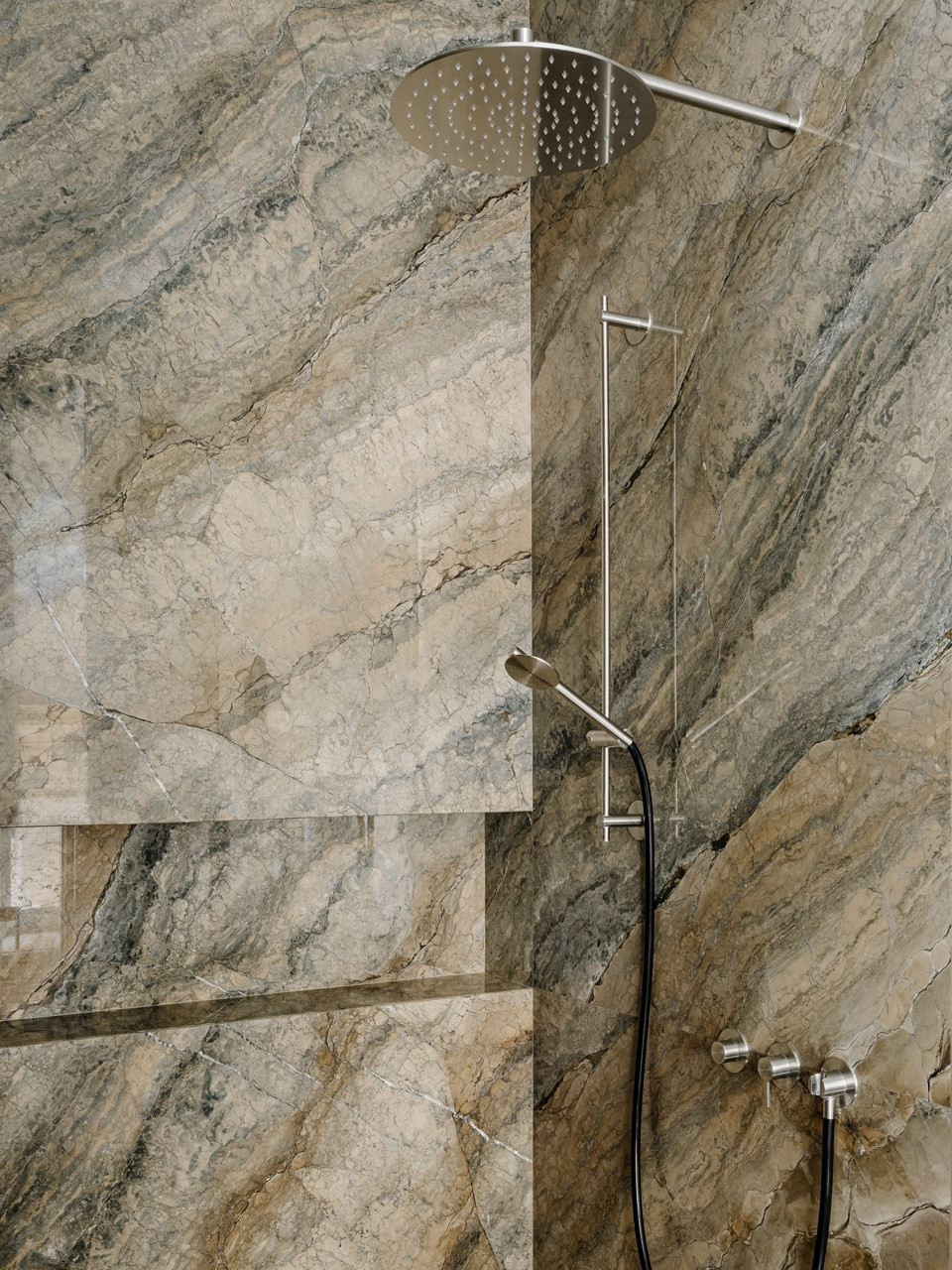 Natural stone shower walls showcasing the dramatic veining of the marble in the master bathroom