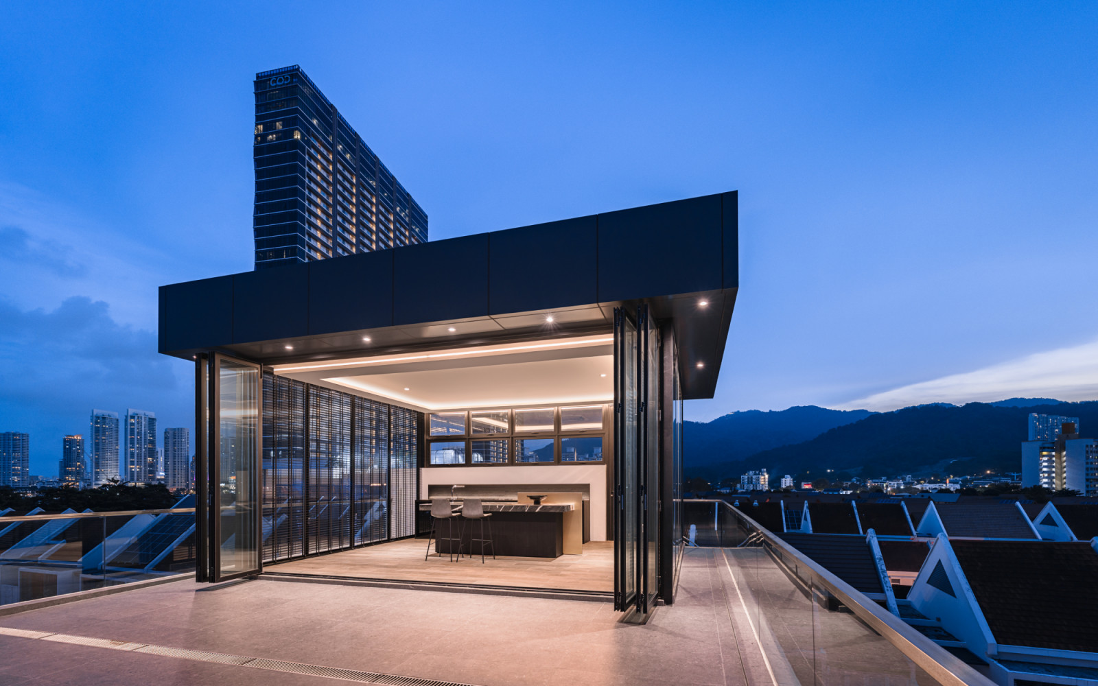 The rooftop entertainment area’s sophisticated lighting design makes it appear to float above the urban landscape
