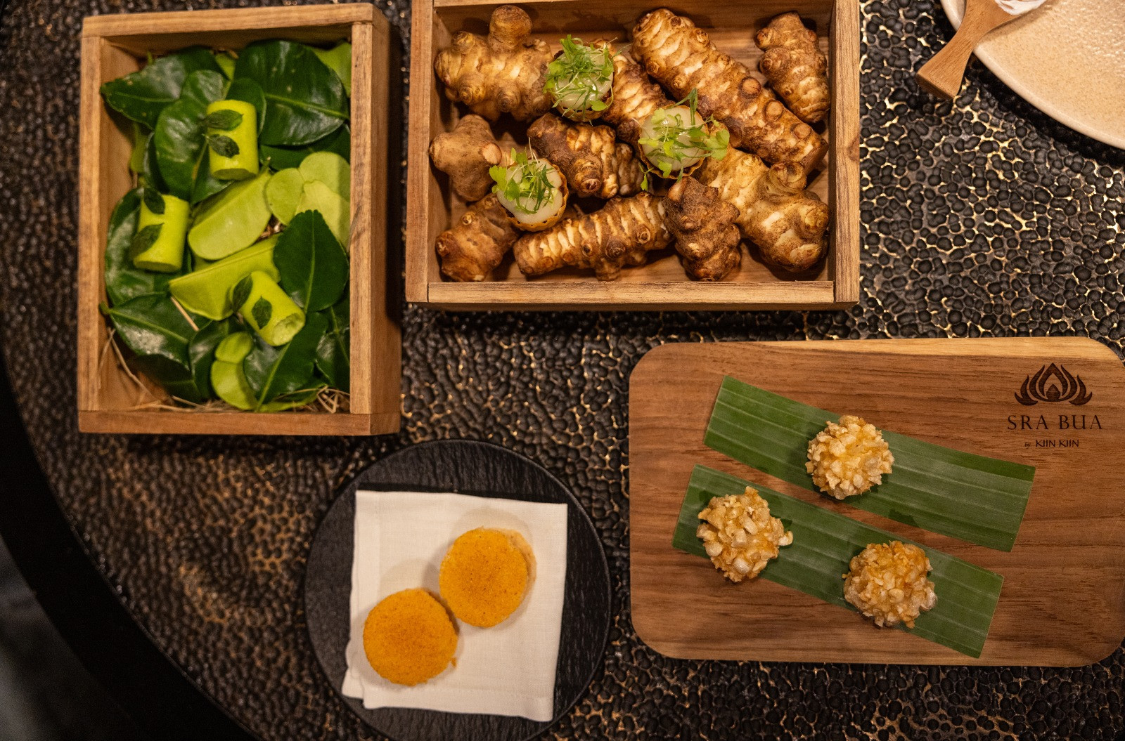 เมนูเรียกน้ำย่อยอย่าง Pork Cracklings Vegetable Puff แคบหมูน้ำพริกหนุ่มในเวอร์ชั่นที่อัดแน่นอยู่ในลูกกลมๆ และ Curry Tasting ที่รวมเอาแกงสามชนิดมานำเสนอในแต่ละคำ ตั้งแต่แกงเขียวหวานในรูปแบบมูส ไปจนถึงมัสมั่นแกะที่เสิร์ฟพร้อมครีมมันแกว (ภาพ: Worapon Teerawatvijit)