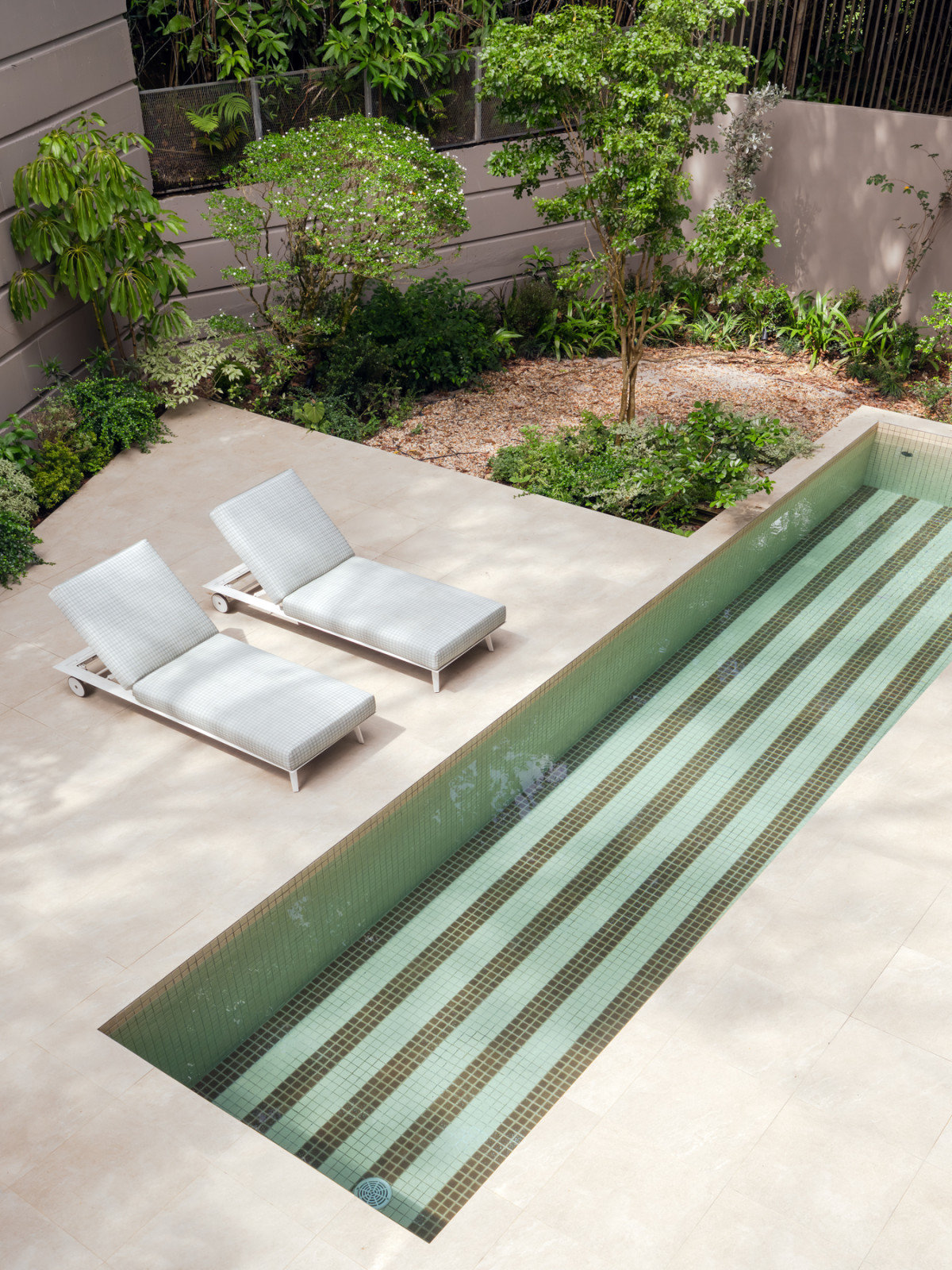 The neutral-toned patio floor tiles and pool mosaics, paired with brown mosaic tiles that act as “sensory activators”