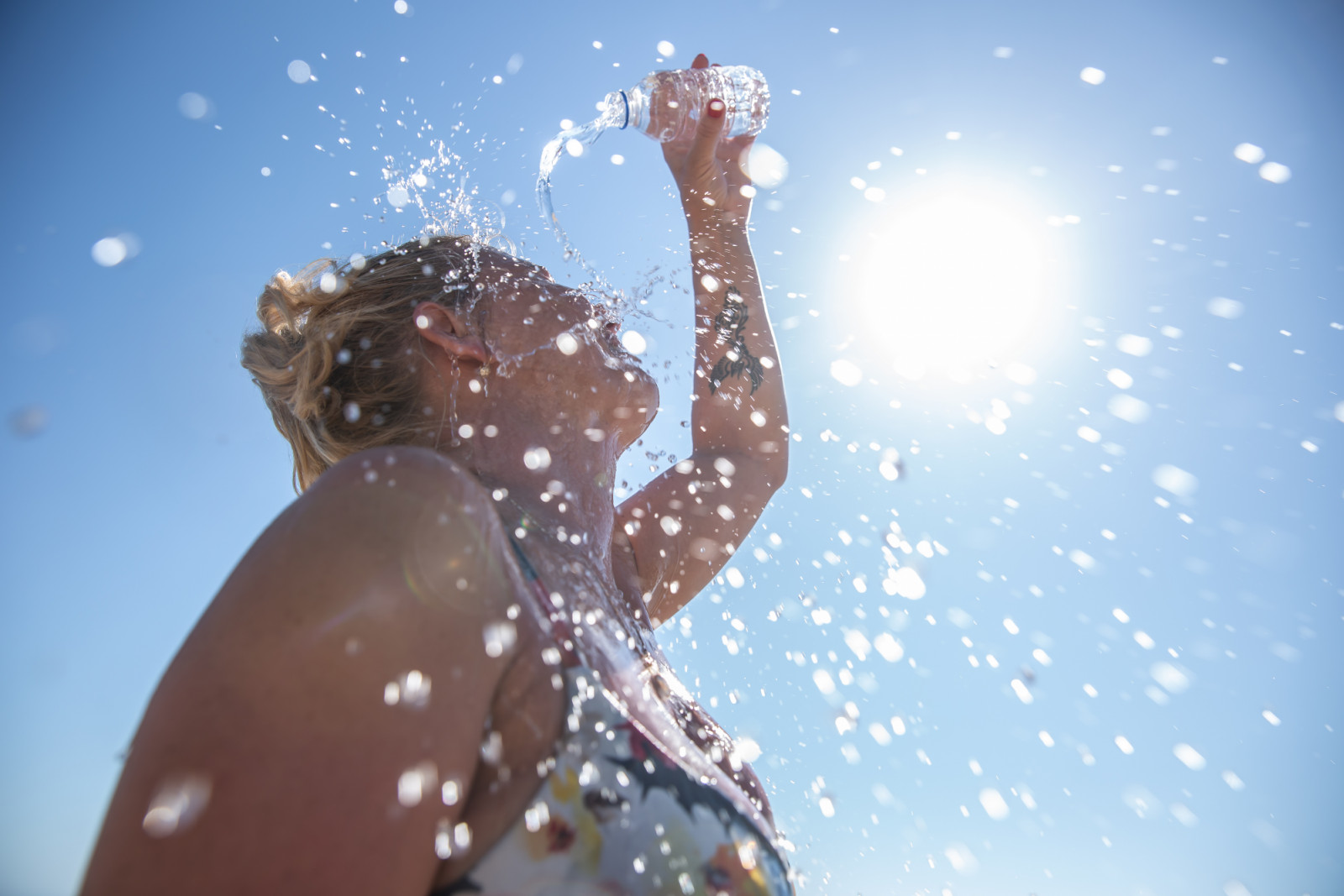 A young woman cools down with cold water during the summer heat.