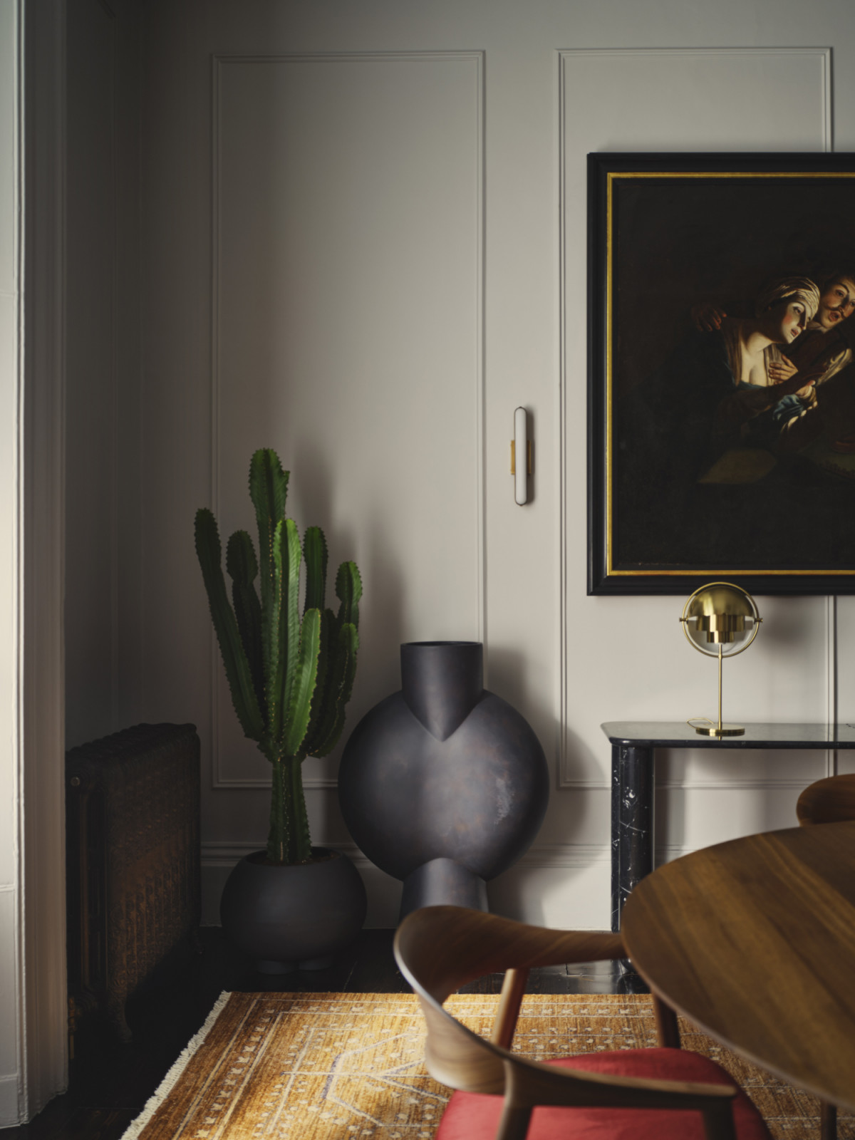 The dining room in a Dublin, Ireland home designed by Maison RA-D with a Multi Lite table lamp by Gubi, Sunday Console by La Chance, DK3 dining table, Hera Dining Chair by Pedrali, Stadium Wall light
by Square in Circle, Urchin Plant Pot by 101CPH, Sphere Vase Buble by 101CPH, and Bresle Rug by Soho Home