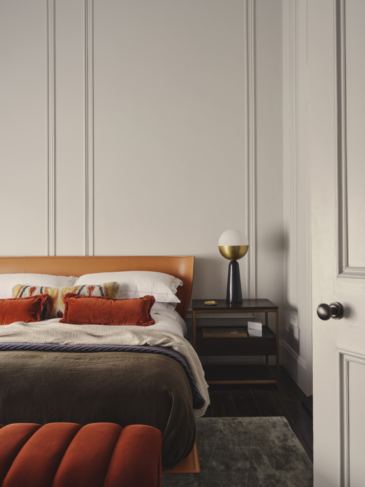 The bedroom of a Dublin, Ireland home designed by Maison RA-D, with an Alys Bed by B&B ITALIA, Globe Table Lamp by Square in Circle, side tables by Eicholtz, Edge Rug by Linie Design, Willis Bench by Soho Home, Margeaux Oblong Cushions + Alderton cushion by Soho Home, and navy herringbone blankets by Johnstons of Elgin