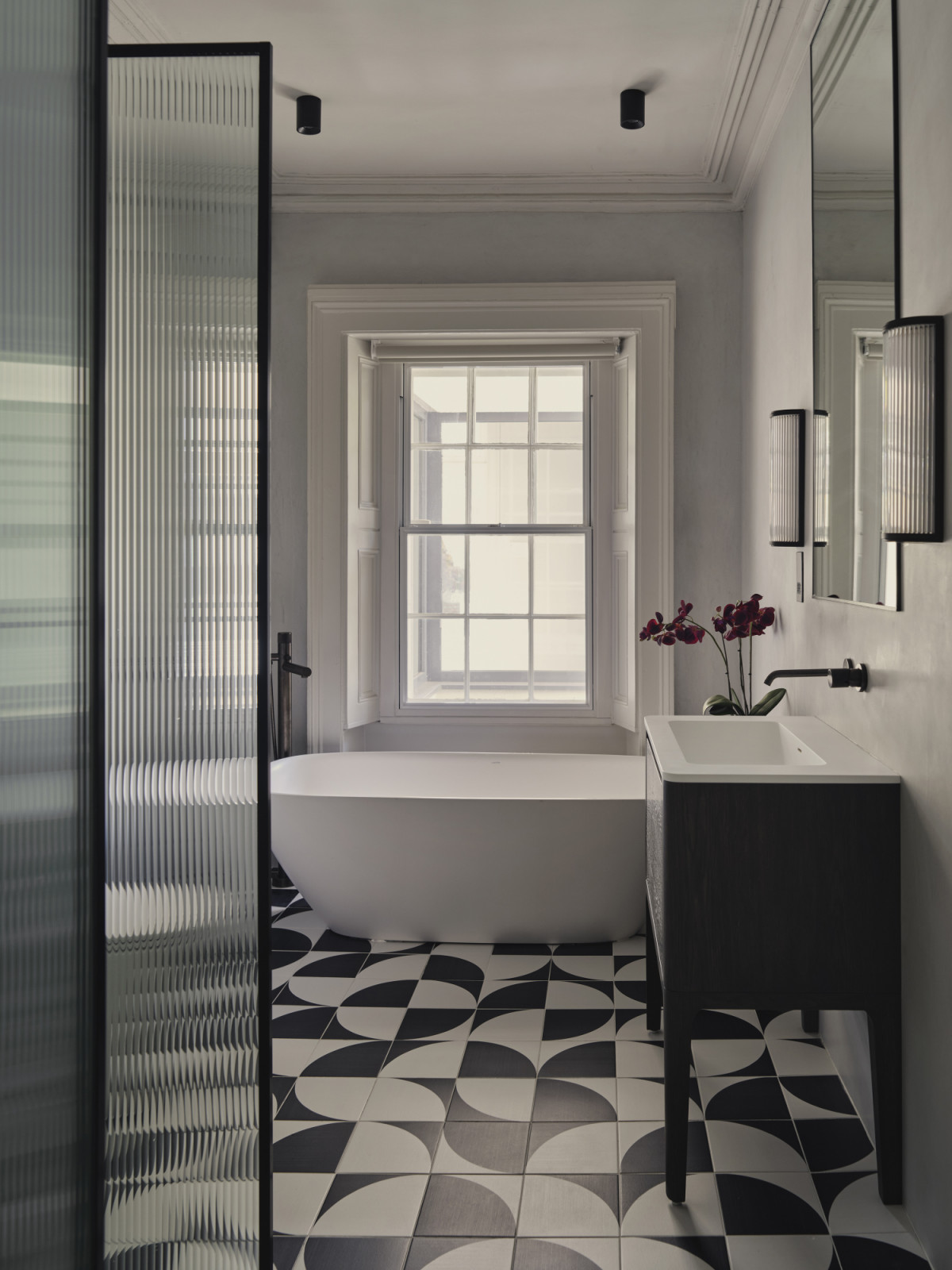 The primary bathroom in a Dublin, Ireland home designed by Maison RA-D, with a Rigo Towel Warmer by Antonio Lupi, Collect Hook Space Copenhagen by AndTradition, microcement wall, tiling in Play Edge Mix by ABK, shower and tap fittings by Gattoni, and bespoke joinery by DFL