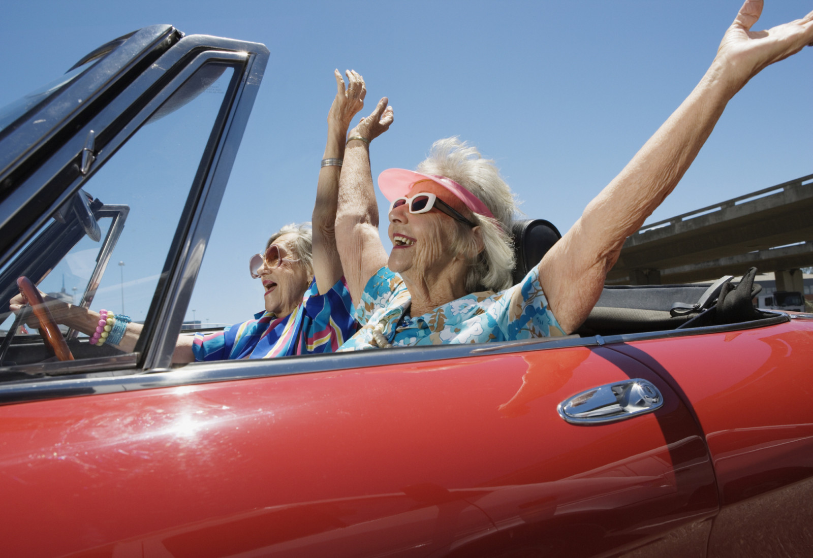 Two senior women in a convertible car, arms outstretched (Photo: Getty Images)